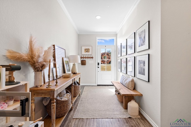 entryway with ornamental molding, wood finished floors, and baseboards