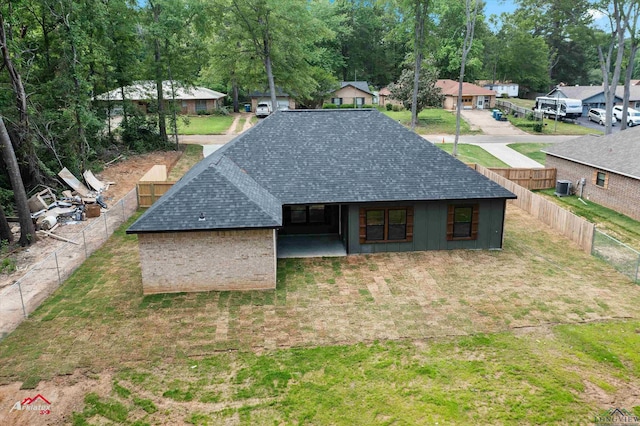 exterior space with central AC, a lawn, fence, roof with shingles, and a residential view