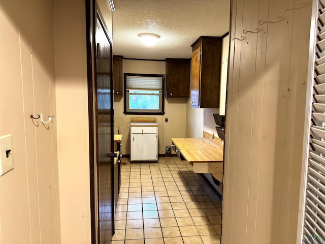 kitchen with dark brown cabinets, a textured ceiling, and light tile patterned floors