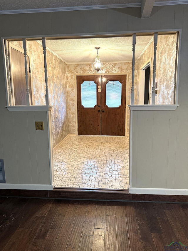 foyer entrance with beamed ceiling, french doors, dark hardwood / wood-style floors, and ornamental molding