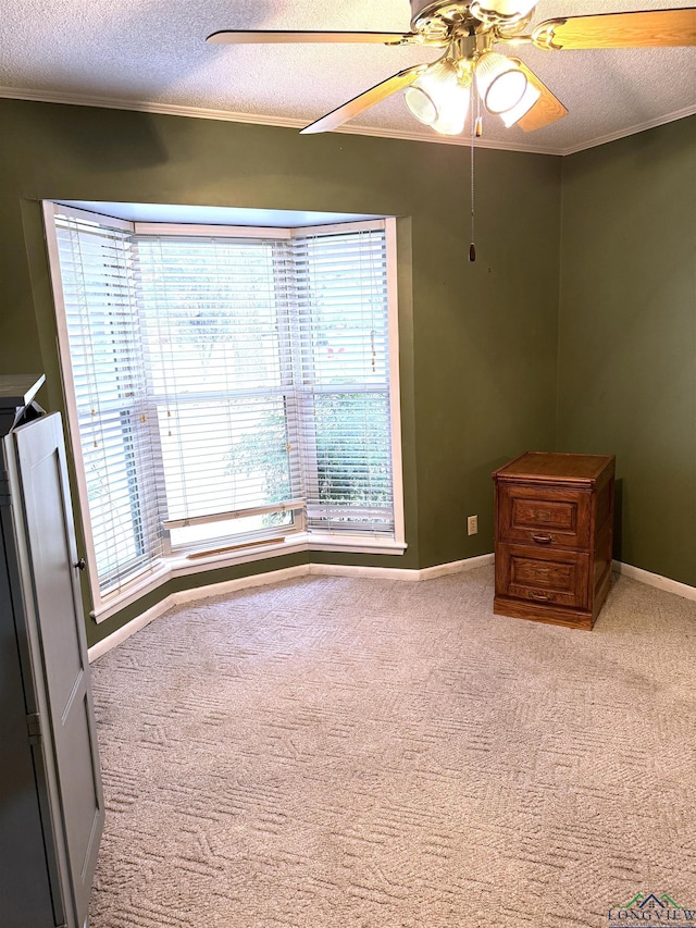 carpeted empty room featuring ceiling fan, a healthy amount of sunlight, a textured ceiling, and ornamental molding