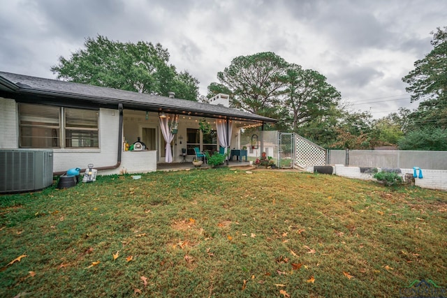 back of house featuring central air condition unit, a patio area, and a lawn