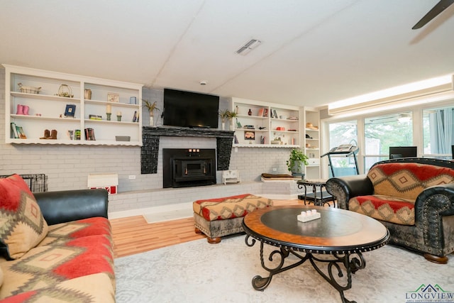 living room with ceiling fan, light hardwood / wood-style floors, and a brick fireplace