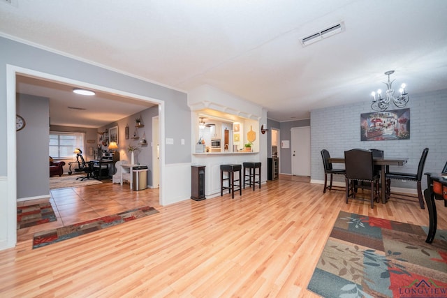 living room with hardwood / wood-style flooring, an inviting chandelier, and brick wall