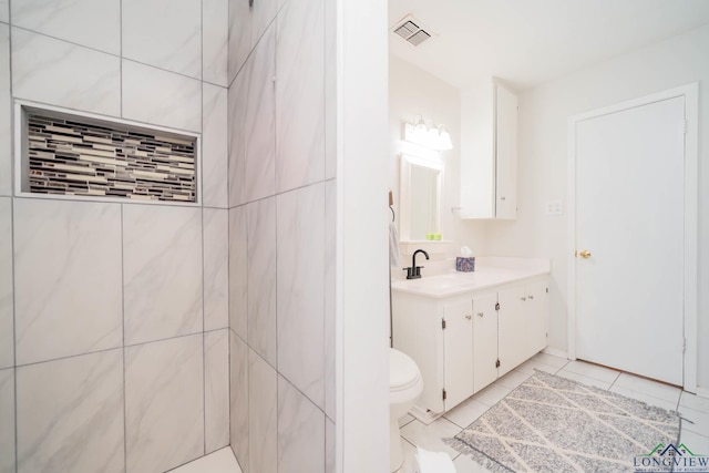 bathroom with toilet, vanity, and tile patterned floors