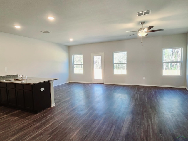 unfurnished living room featuring ceiling fan, dark wood-type flooring, and sink