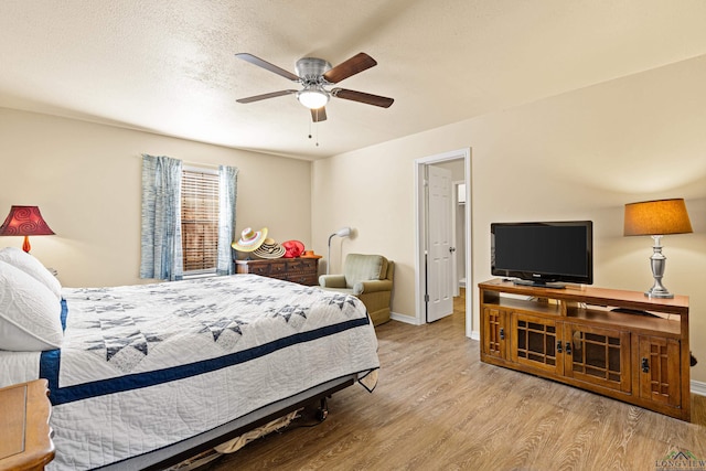 bedroom featuring wood finished floors, baseboards, a ceiling fan, and a textured ceiling
