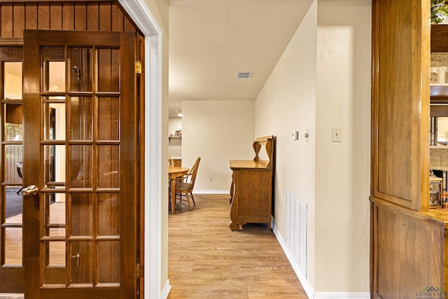 hall with light wood-style floors and baseboards