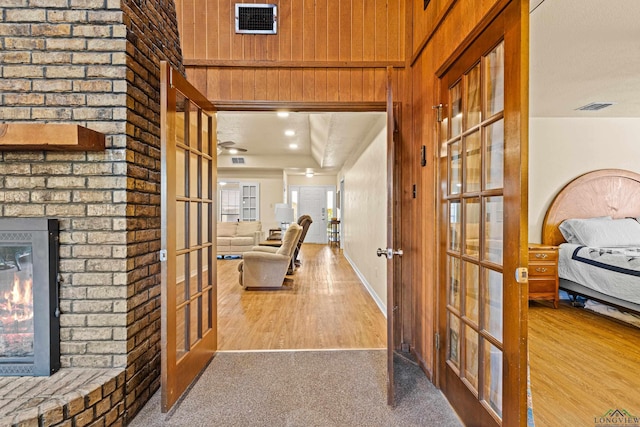 hallway featuring french doors, wood finished floors, carpet flooring, and wood walls