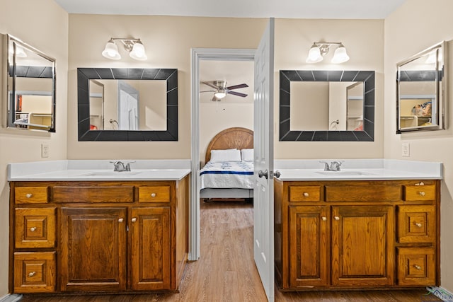 ensuite bathroom with a ceiling fan, wood finished floors, and two vanities