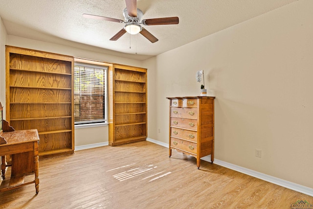 bedroom with wood finished floors, a textured ceiling, baseboards, and ceiling fan