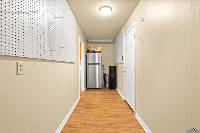 corridor featuring light wood finished floors and baseboards