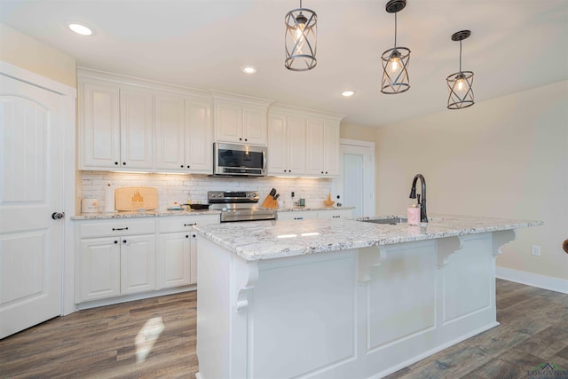kitchen with stainless steel appliances, a sink, dark wood finished floors, white cabinets, and recessed lighting