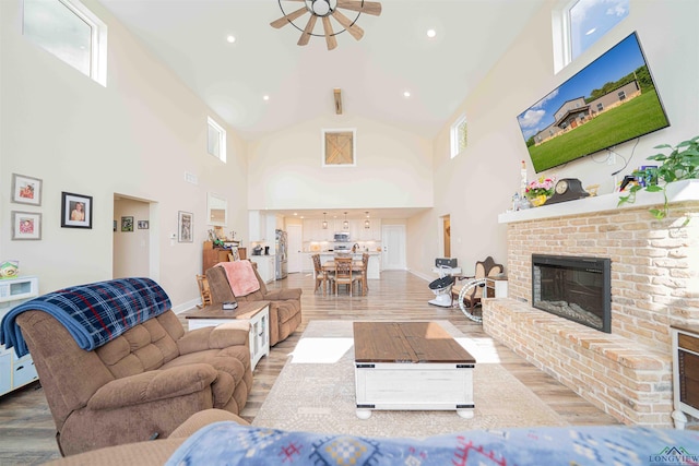 living area featuring high vaulted ceiling, wood finished floors, a fireplace, baseboards, and recessed lighting
