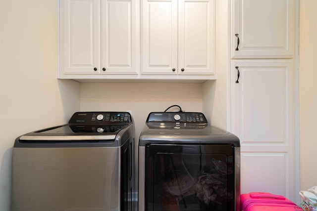clothes washing area featuring washing machine and clothes dryer and cabinet space