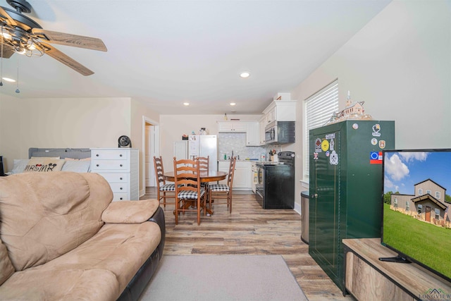 living room featuring light wood-type flooring, a ceiling fan, and recessed lighting