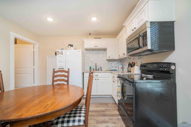 kitchen with black range with electric cooktop, white fridge with ice dispenser, white cabinets, stainless steel microwave, and wood finished floors