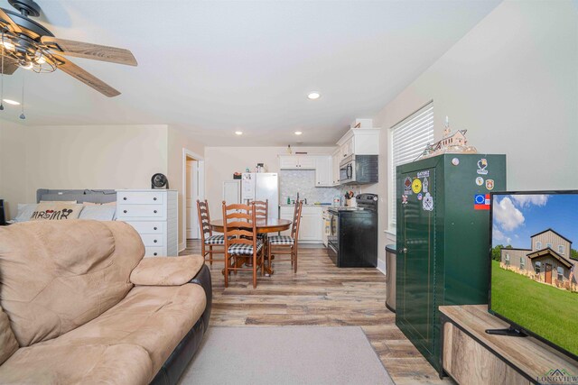 living area featuring light wood-type flooring, a ceiling fan, and recessed lighting