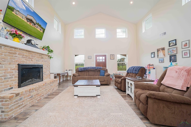 living area with wood finished floors, high vaulted ceiling, and a fireplace