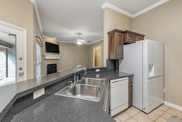 kitchen with sink, a tiled fireplace, ornamental molding, light tile patterned floors, and white appliances