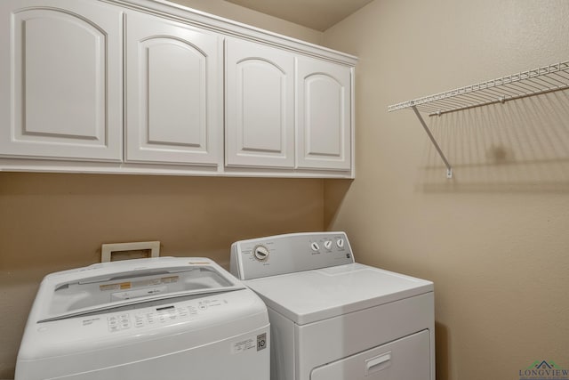 laundry area with separate washer and dryer and cabinets