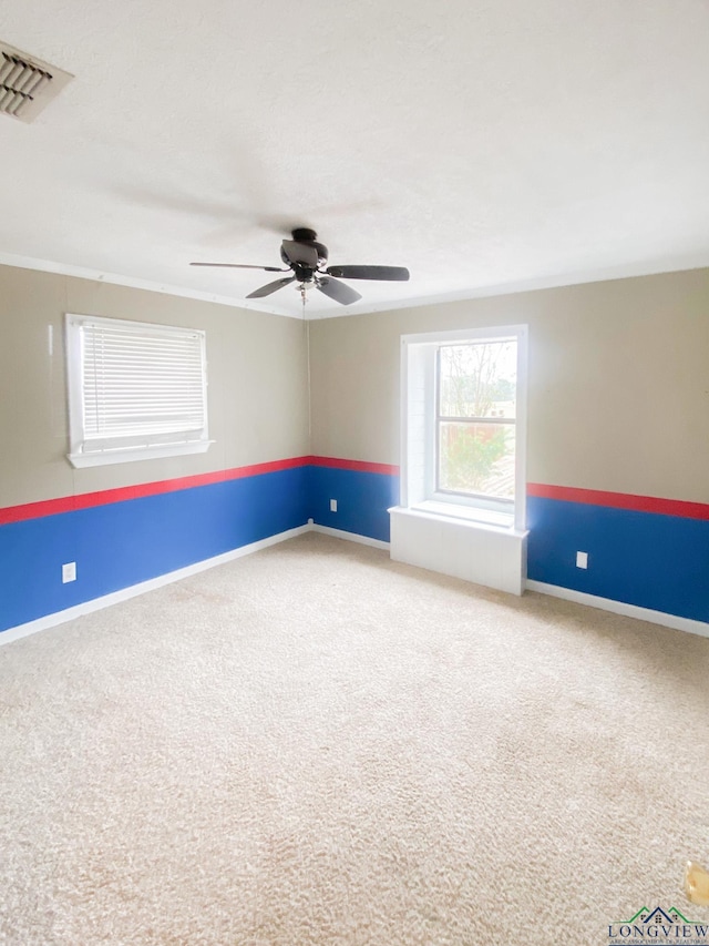 empty room with ceiling fan, carpet floors, and ornamental molding