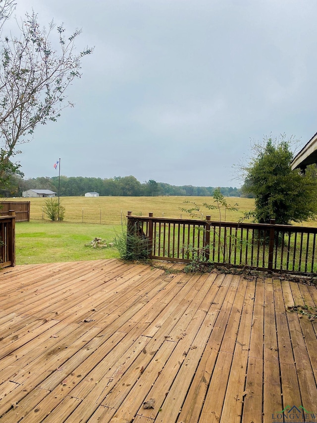 wooden terrace featuring a lawn and a rural view