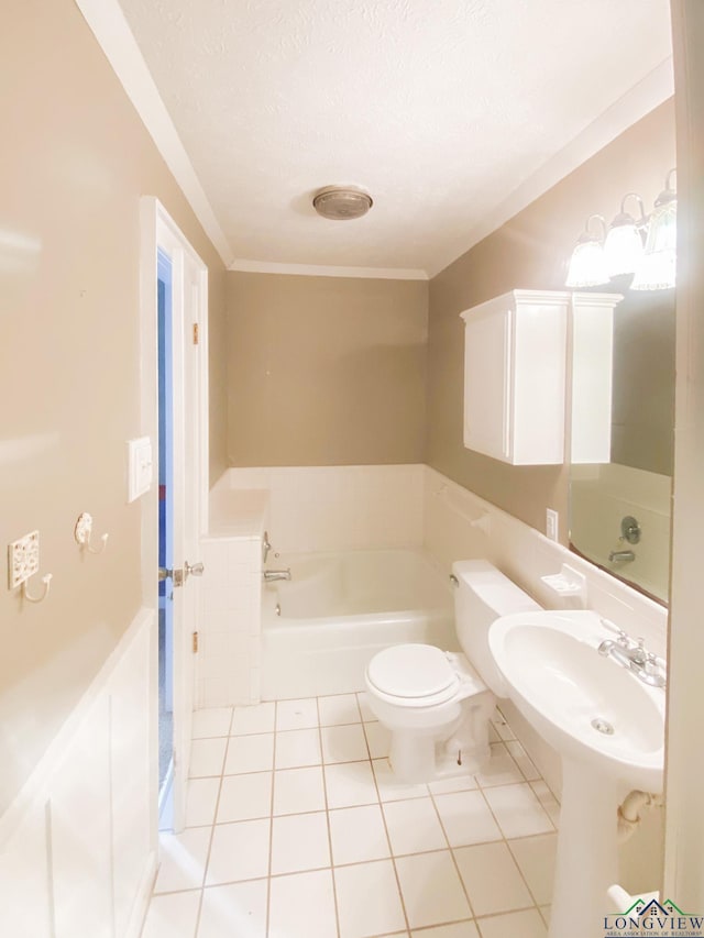 bathroom featuring tile patterned floors, a tub to relax in, crown molding, a textured ceiling, and toilet