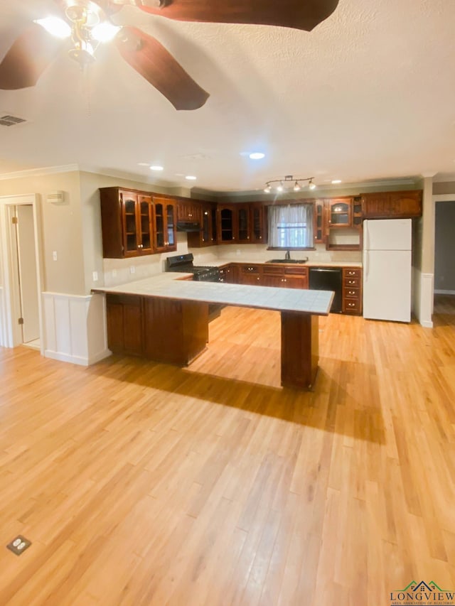 kitchen featuring kitchen peninsula, light wood-type flooring, a breakfast bar, and black appliances