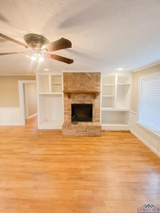 unfurnished living room with ceiling fan, built in features, light hardwood / wood-style floors, and ornamental molding