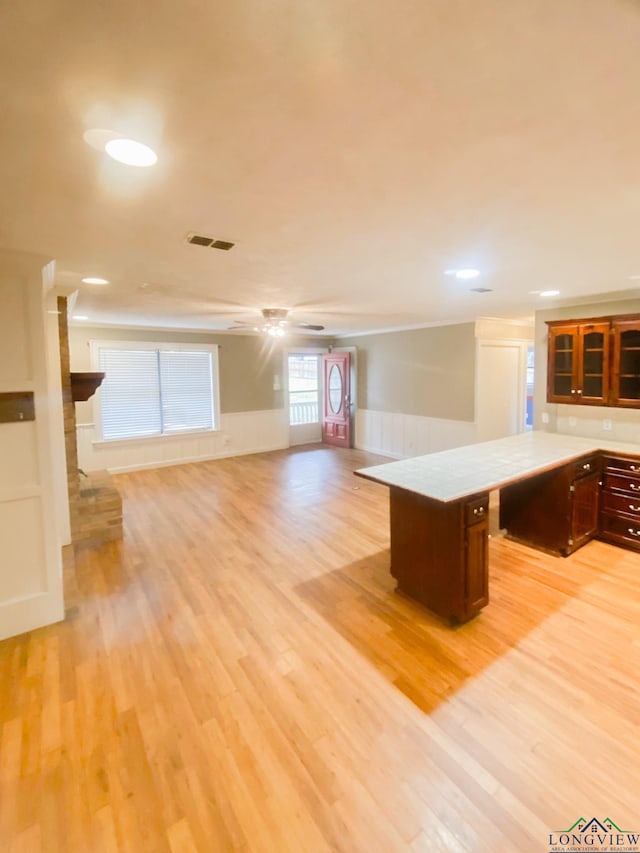 kitchen with ceiling fan, a center island, light wood-type flooring, and a fireplace