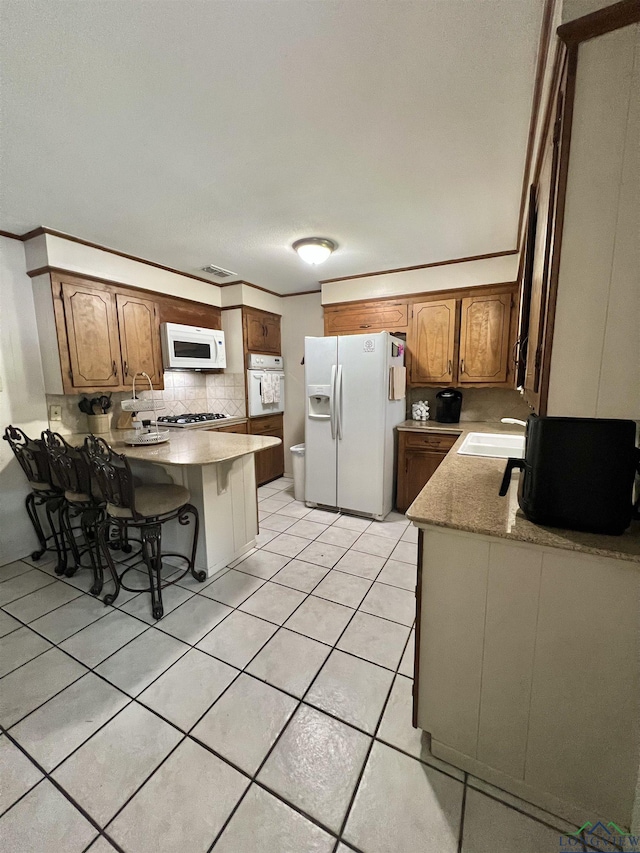 406 Campbell St, Daingerfield, TX 75638 - kitchen featuring white appliances, a peninsula, decorative backsplash, light tile patterned floors, and light countertops