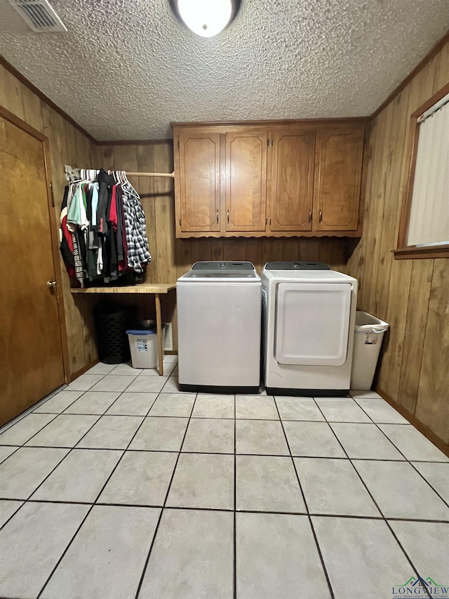 406 Campbell St, Daingerfield, TX 75638 - laundry area featuring cabinet space, washing machine and dryer, wood walls, a textured ceiling, and light tile patterned floors