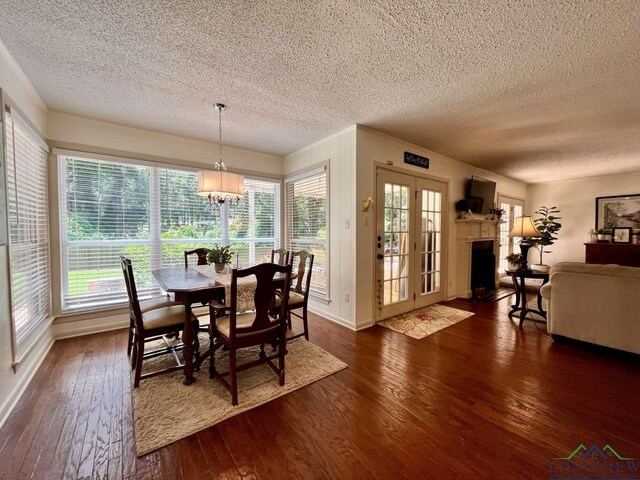 16 Pegues Pl, Longview, TX 75601 - dining room with a textured ceiling, dark wood-type flooring, healthy amount of natural light, a chandelier, and a fireplace