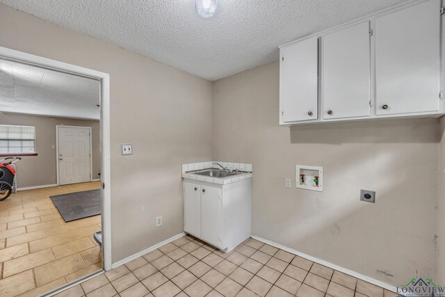 2202 Woodbine Dr, Gladewater, TX 75647 - washroom featuring electric dryer hookup, washer hookup, cabinet space, a textured ceiling, and light tile patterned floors