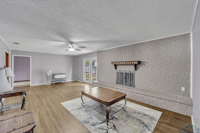 2202 Woodbine Dr, Gladewater, TX 75647 - living room with ceiling fan, wood finished floors, ornamental molding, a textured ceiling, and a fireplace