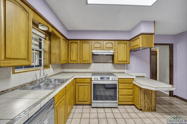 2202 Woodbine Dr, Gladewater, TX 75647 - kitchen with stainless steel appliances, backsplash, under cabinet range hood, and tile countertops