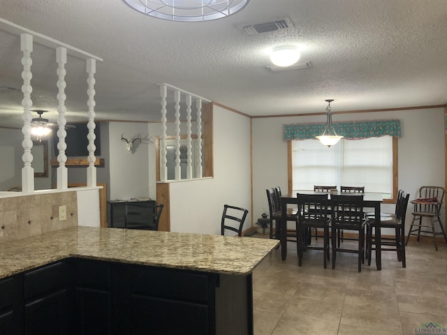 kitchen with kitchen peninsula, a textured ceiling, hanging light fixtures, and crown molding