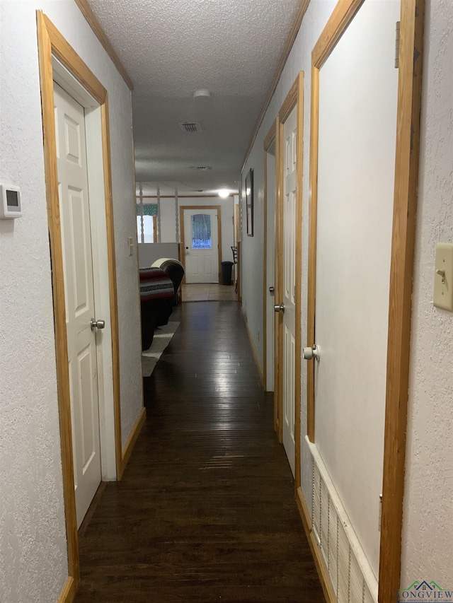 hall with dark hardwood / wood-style flooring, a textured ceiling, and crown molding