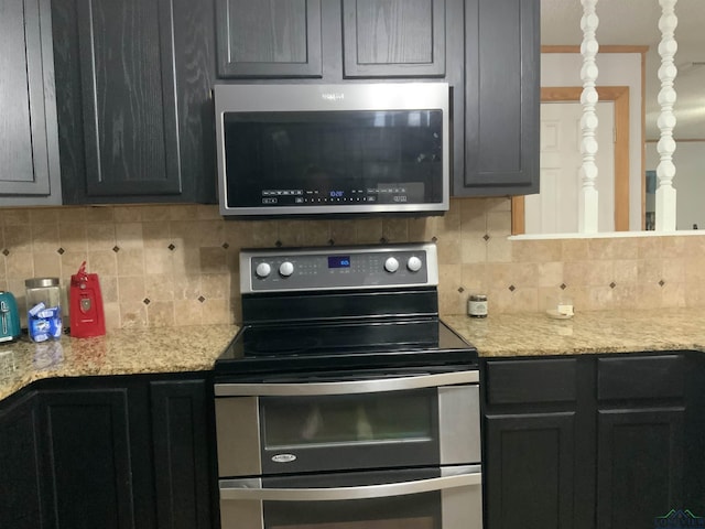 kitchen with light stone countertops, backsplash, and appliances with stainless steel finishes