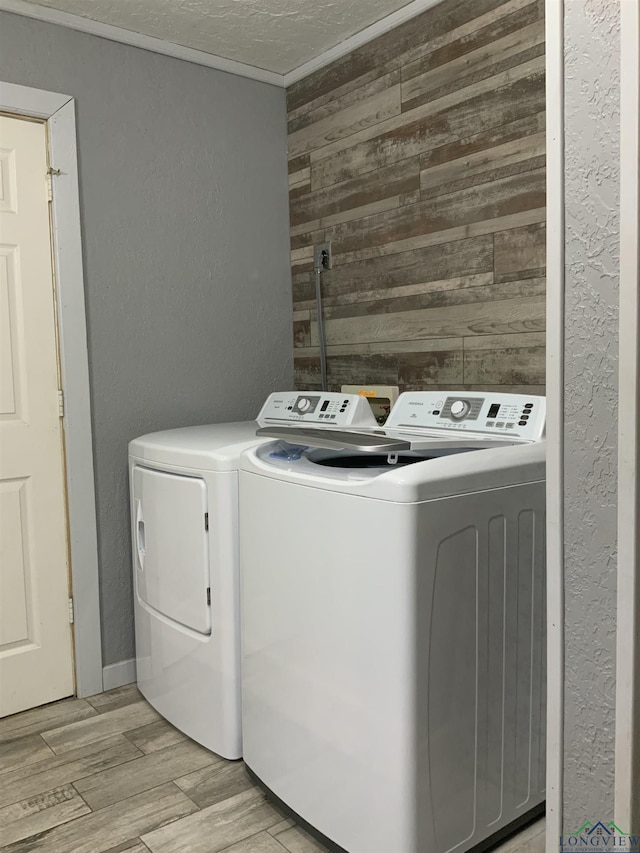 clothes washing area with washing machine and dryer, wooden walls, and ornamental molding