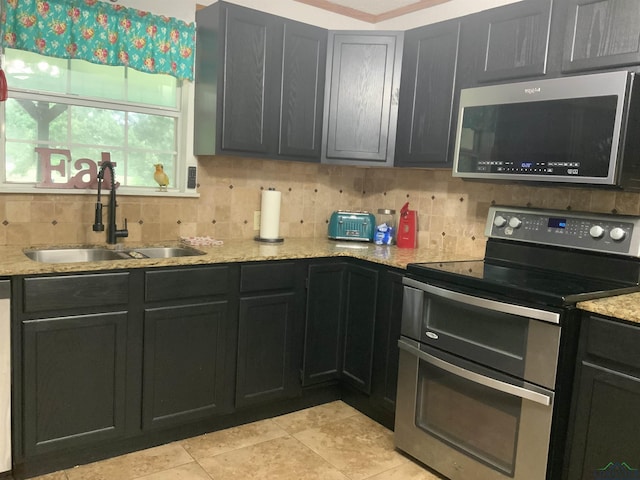 kitchen featuring decorative backsplash, light stone counters, sink, and stainless steel appliances