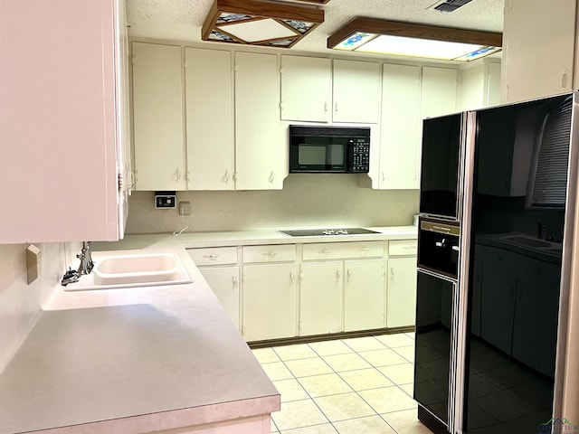 kitchen with black appliances, light tile patterned flooring, white cabinets, and sink