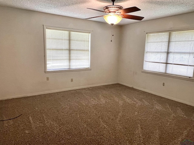 carpeted empty room with a textured ceiling, plenty of natural light, and ceiling fan