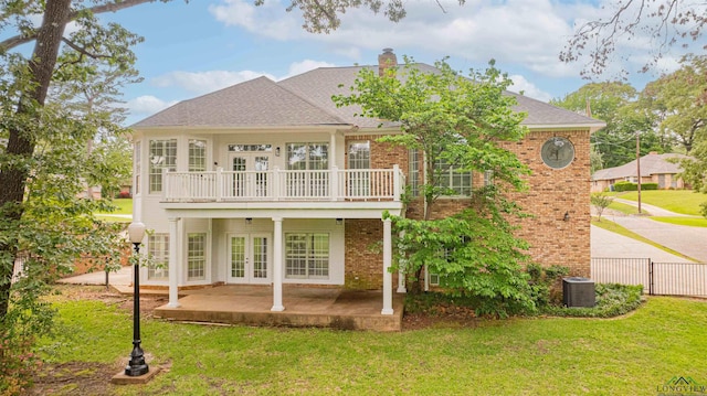 rear view of property with french doors, a lawn, and brick siding