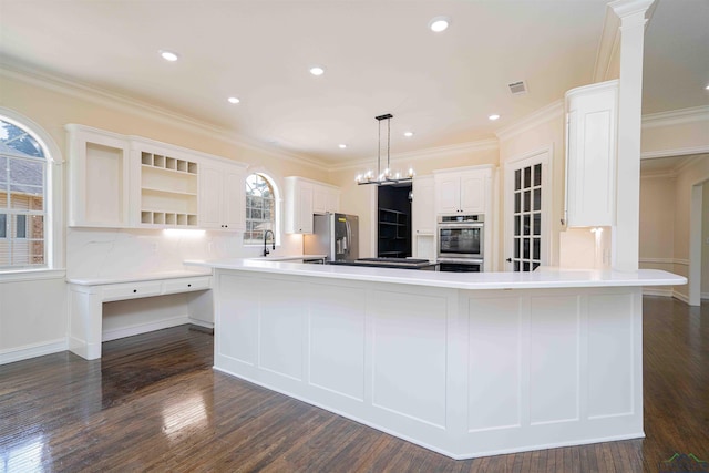 kitchen with white cabinets, crown molding, appliances with stainless steel finishes, a sink, and a peninsula