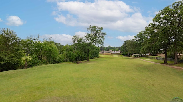 view of property's community featuring fence, a lawn, and golf course view