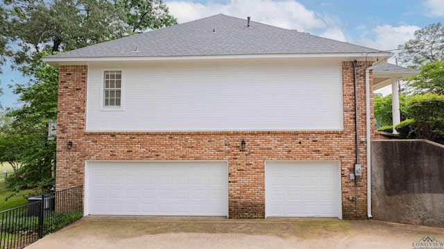 view of home's exterior featuring a garage, fence, roof with shingles, brick siding, and concrete driveway