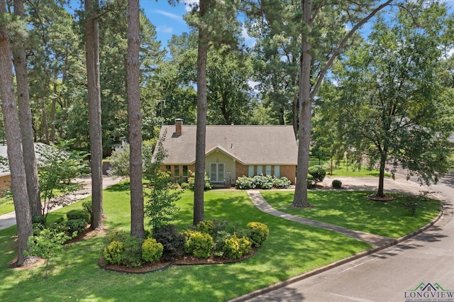 1800 Shady Ln, Longview, TX 75604 - view of front of home with a front yard, a chimney, view of wooded area, and roof with shingles