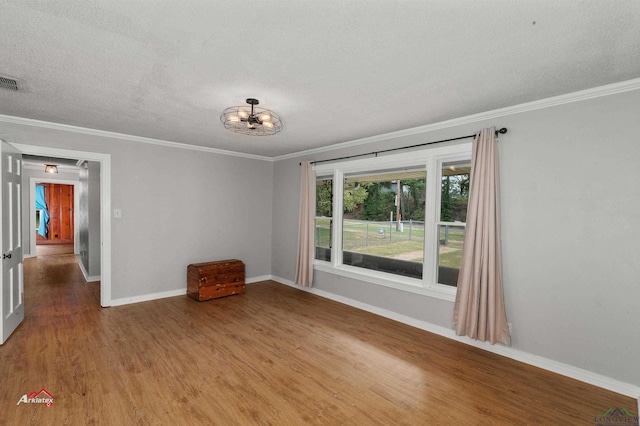 spare room with a textured ceiling, wood-type flooring, and crown molding